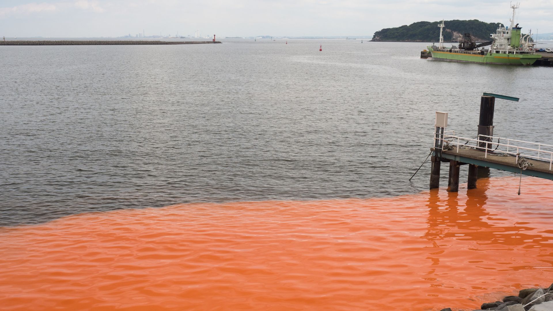 A red tide rolling in past a dock