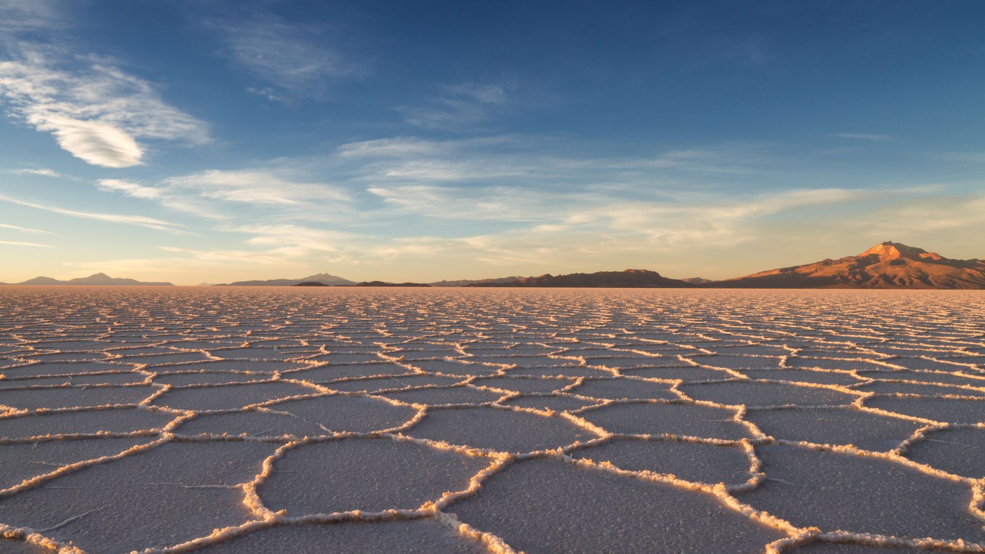 A wide expanse of salt flats with mountains in the distant background
