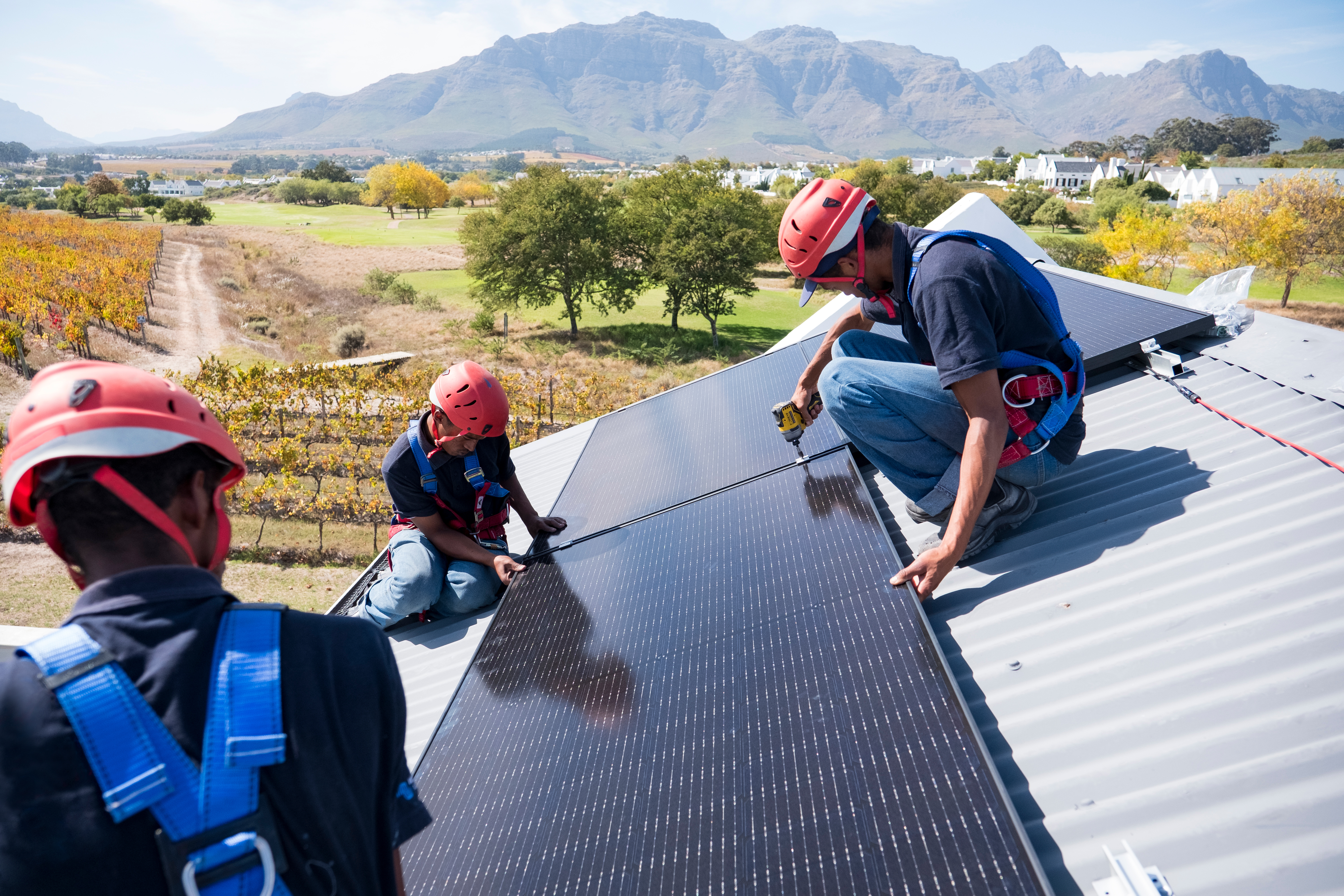 Workers installing solar panels on a roof in Cape Town, South Africa