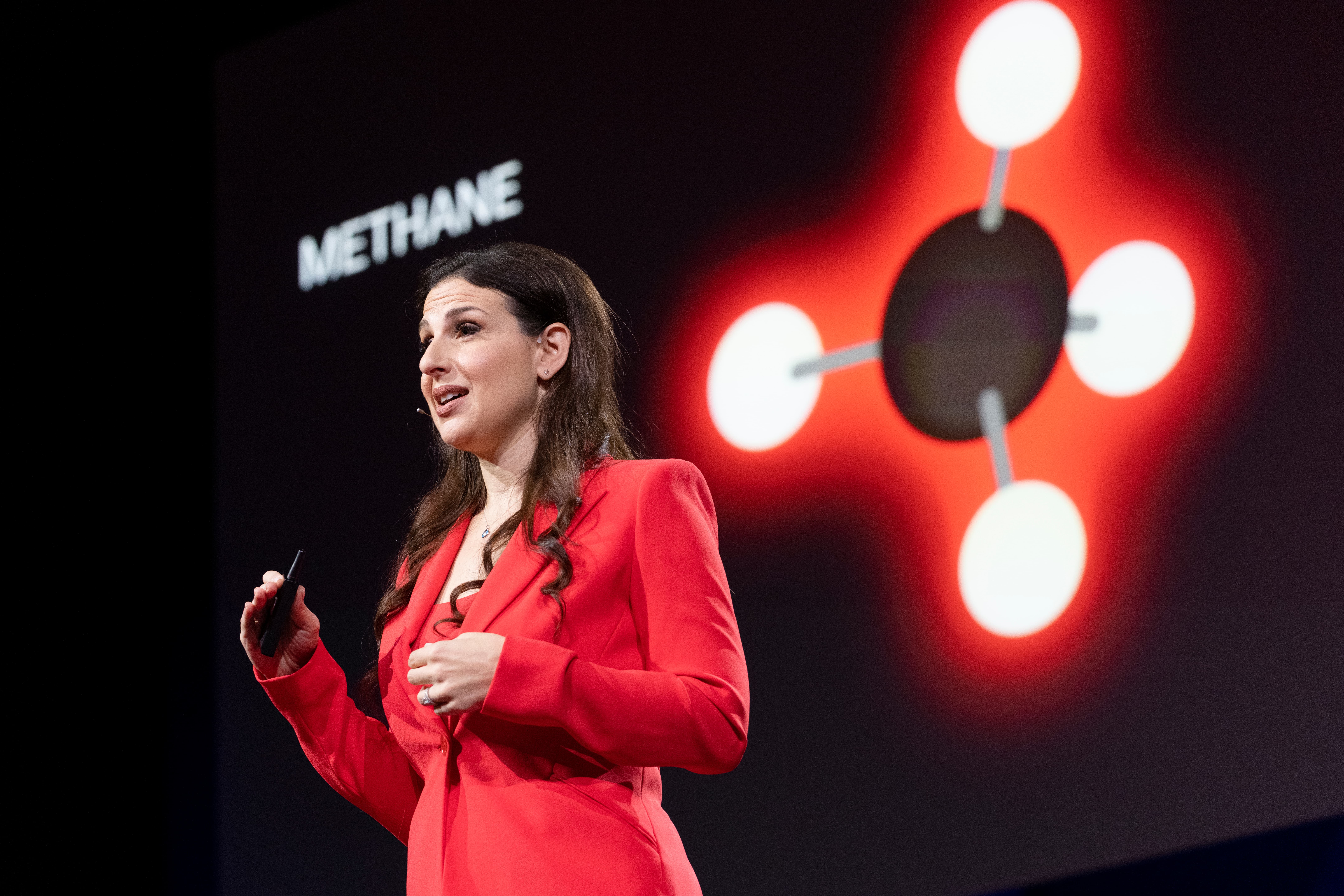 Dr. Ilissa Ocko on the TED stage with a methane molecule on screen behind her