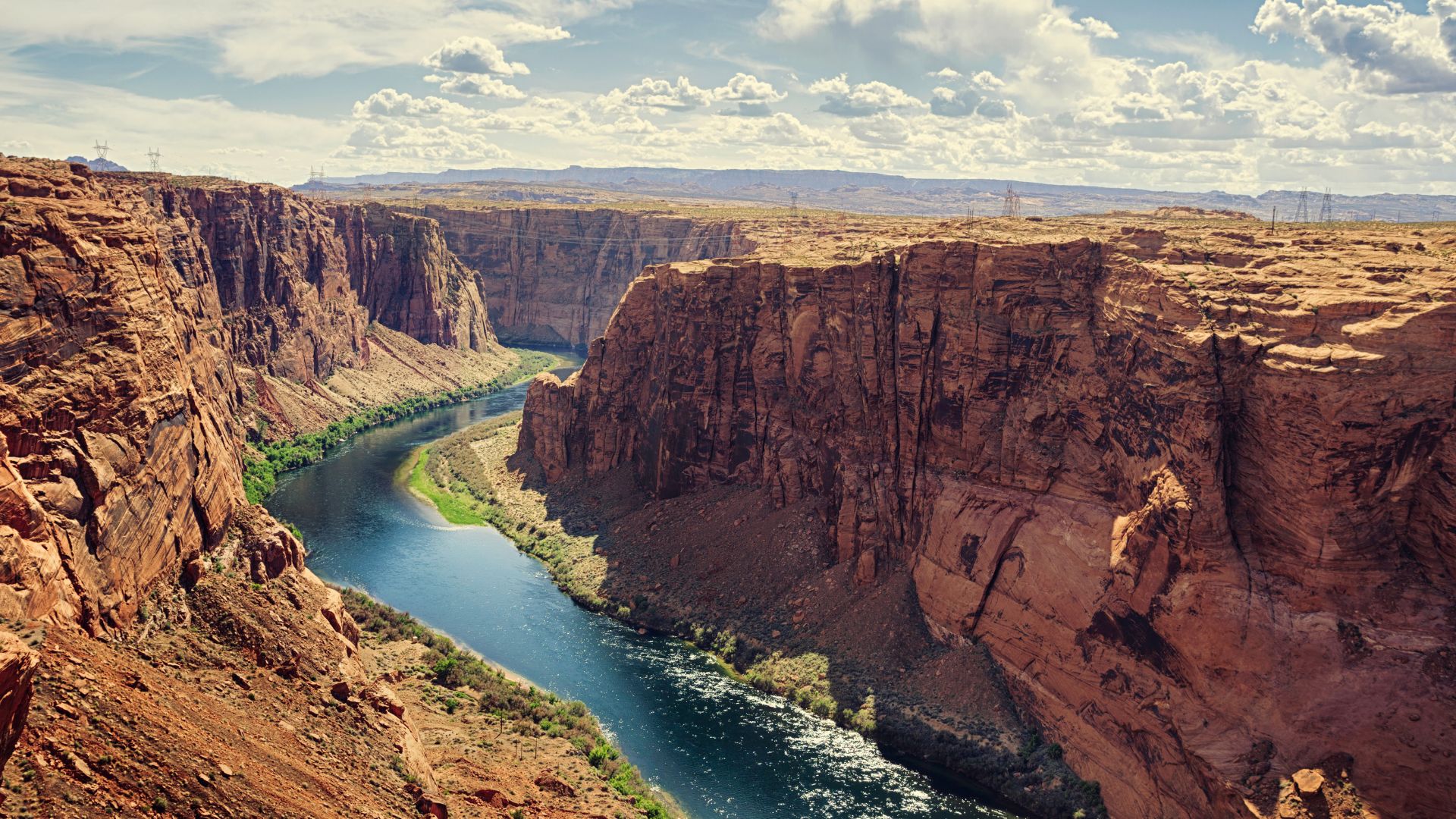 A winding canyon of red rock with a flowing, full river at the bottom