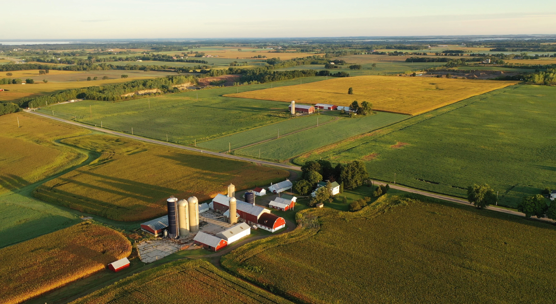 A farm with red barns and silos, viewed from overhead.