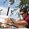 Man mounting monitor to top of car