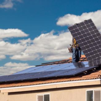 A house with workers actively installing solar panels on the roof