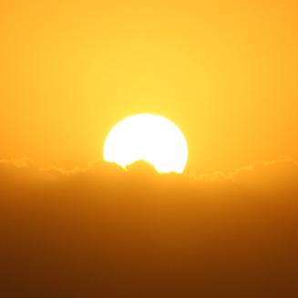 Sun setting behind clouds
