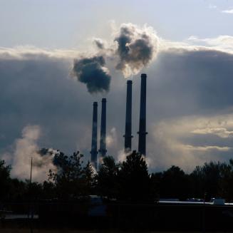 Smokestacks in the distance, releasing clouds of emissions.