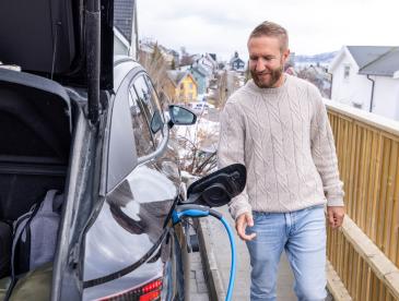 A man charges an electric car at a charging station in Norway.