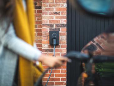A person plugging a charger into an electric vehicle