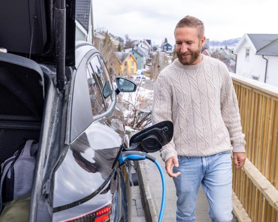 A man charges an electric car at a charging station in Norway.